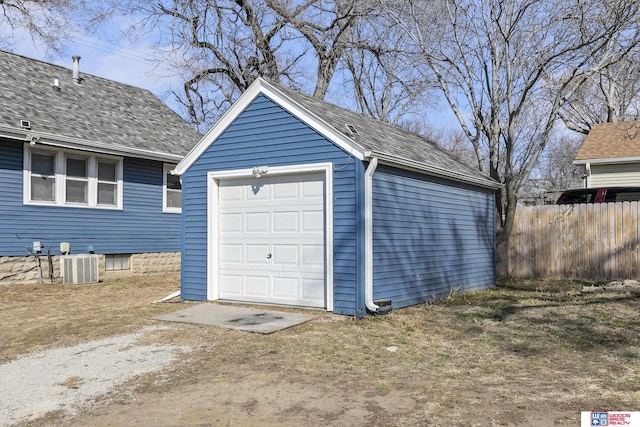 detached garage featuring dirt driveway, central air condition unit, and fence