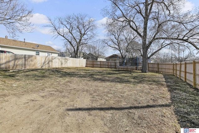 view of yard featuring a trampoline and a fenced backyard