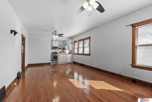 unfurnished living room with baseboards, a healthy amount of sunlight, and hardwood / wood-style floors