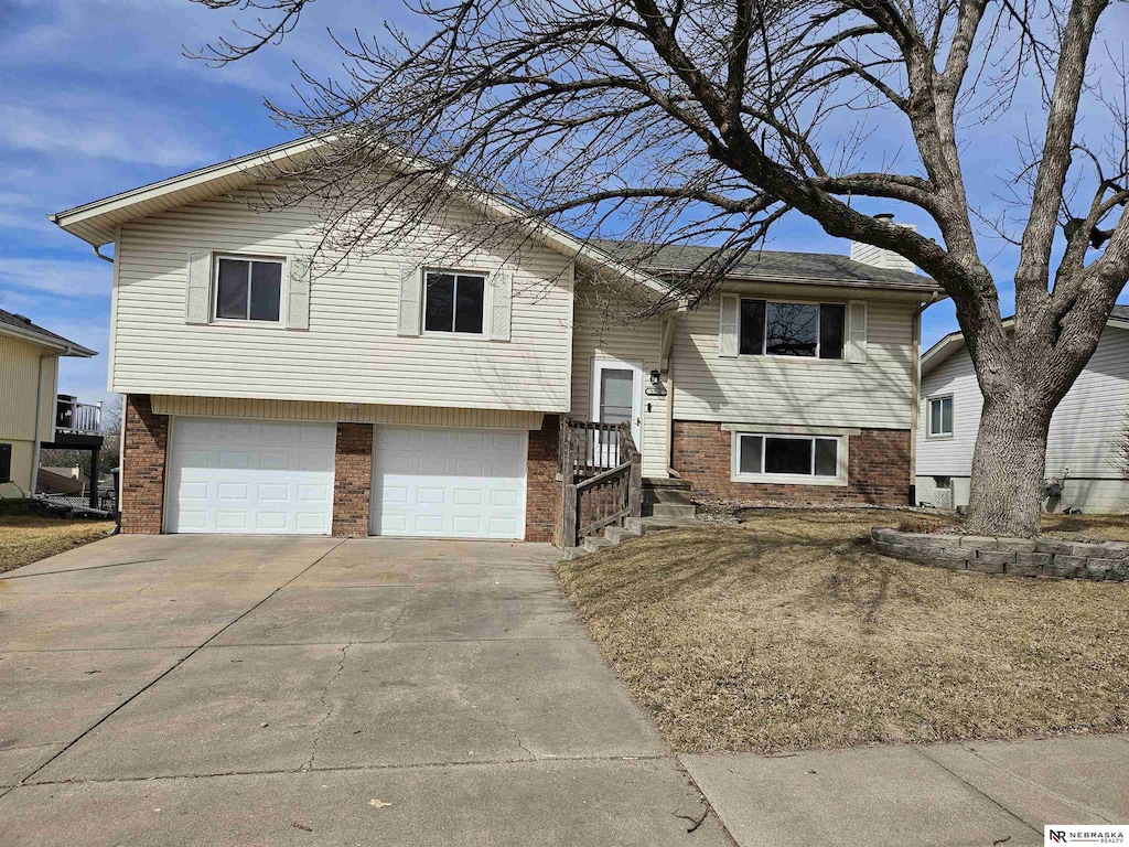 split foyer home with brick siding, concrete driveway, and a garage