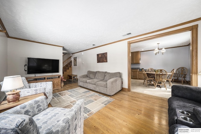 living room with stairs, visible vents, light wood-type flooring, and ornamental molding