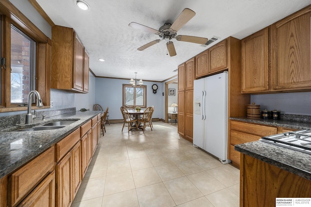 kitchen with a sink, brown cabinets, visible vents, and white fridge with ice dispenser