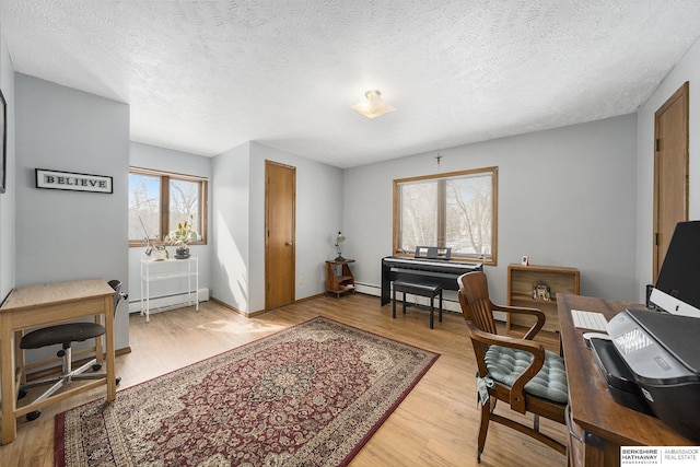 office featuring a baseboard heating unit, light wood-style floors, and a textured ceiling