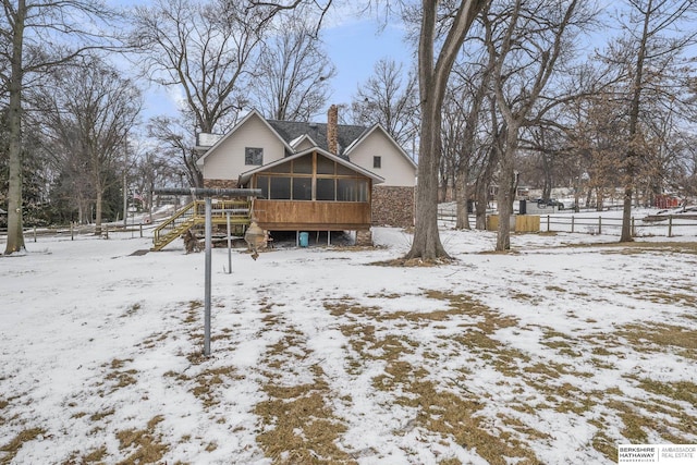 snow covered back of property with fence, a sunroom, and a chimney