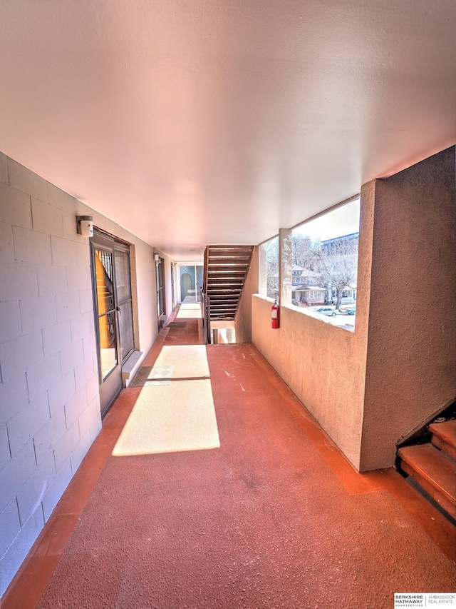 hall featuring stairway and concrete block wall