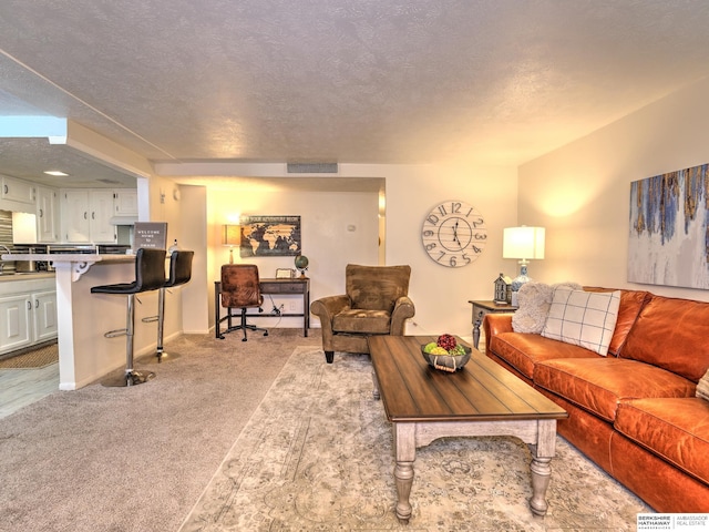 living room featuring visible vents, light colored carpet, and a textured ceiling