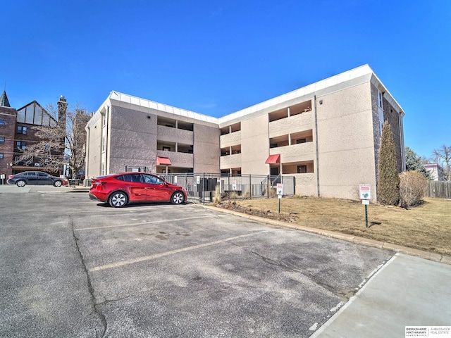 view of building exterior featuring uncovered parking and fence