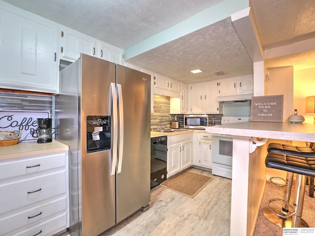 kitchen with decorative backsplash, white cabinets, under cabinet range hood, and stainless steel appliances