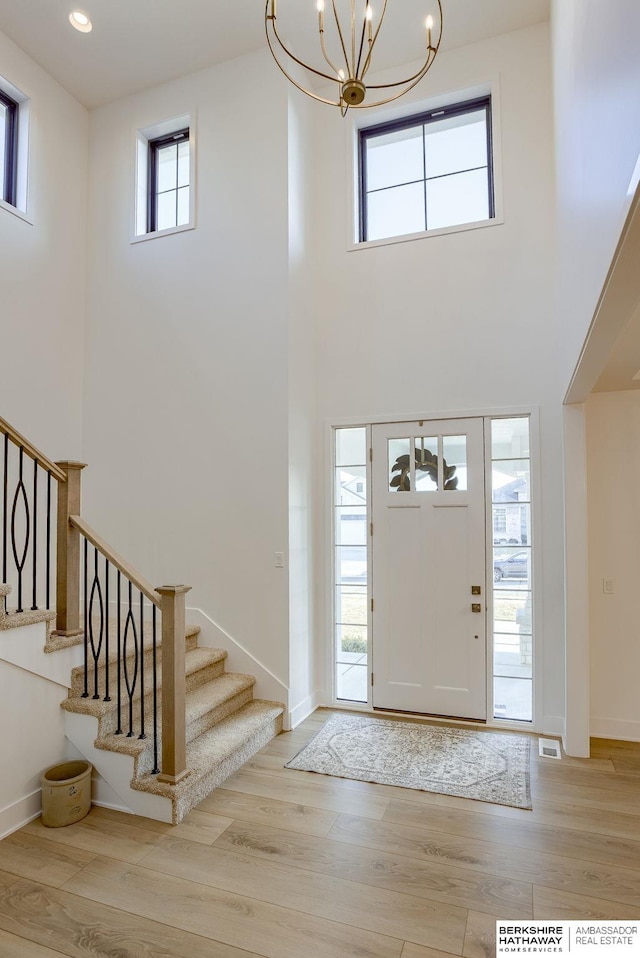 foyer with stairway, a notable chandelier, wood finished floors, and baseboards