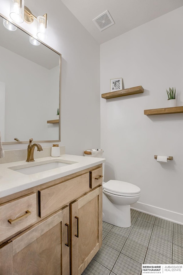 half bathroom featuring vanity, baseboards, visible vents, tile patterned floors, and toilet