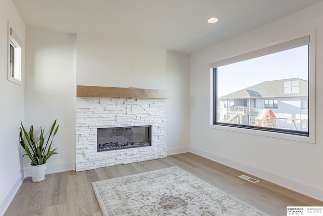 unfurnished living room featuring visible vents, baseboards, wood finished floors, and a fireplace