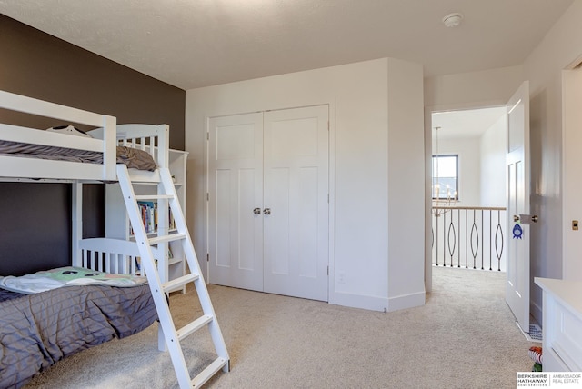 bedroom featuring a notable chandelier, baseboards, a closet, and light carpet