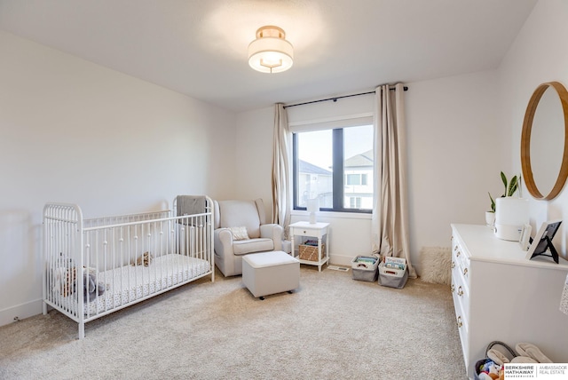 carpeted bedroom featuring a crib and baseboards