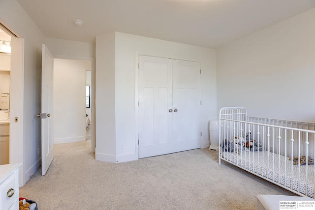 bedroom featuring a closet, baseboards, carpet, and a crib