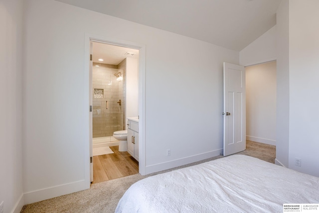 bedroom featuring vaulted ceiling, baseboards, ensuite bathroom, and light carpet