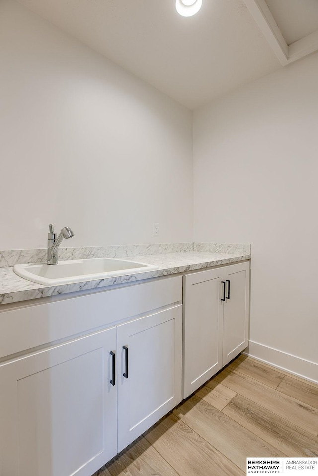 bathroom with wood finished floors, baseboards, and a sink