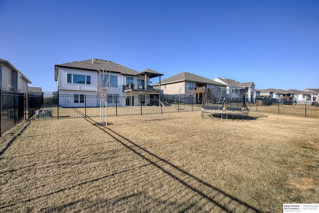 view of yard with a residential view, a trampoline, and a fenced backyard