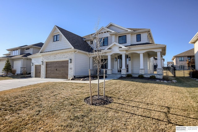 view of front facade with fence, concrete driveway, a front yard, covered porch, and stone siding