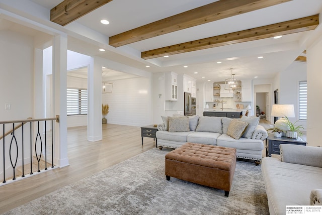 living area with beam ceiling, an inviting chandelier, and a healthy amount of sunlight