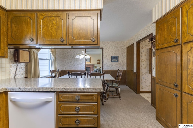 kitchen with brown cabinetry, wainscoting, and wallpapered walls