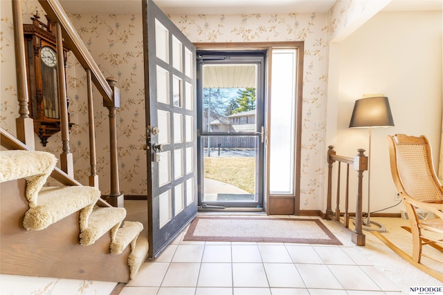 foyer entrance featuring light tile patterned floors, stairway, wallpapered walls, and baseboards