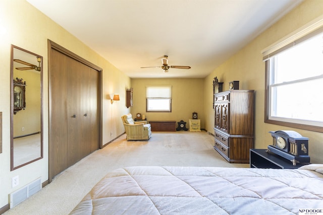 carpeted bedroom featuring visible vents, a closet, ceiling fan, and a wood stove