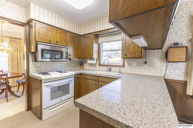 kitchen featuring wallpapered walls, stainless steel microwave, electric stove, and a sink