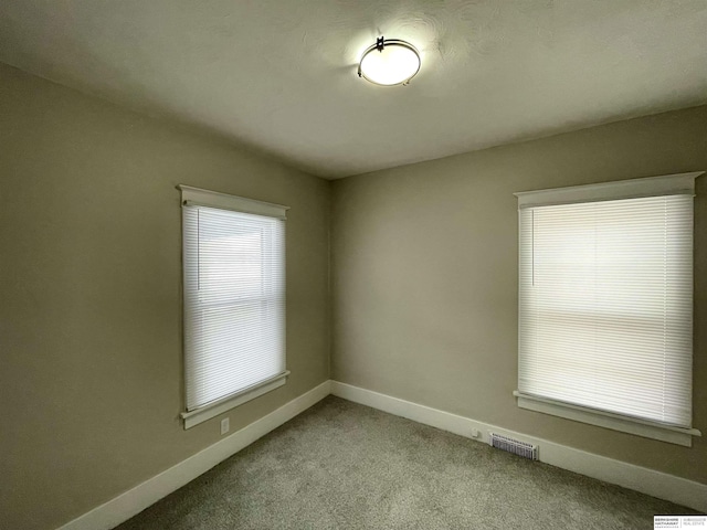 empty room with baseboards, carpet floors, and visible vents