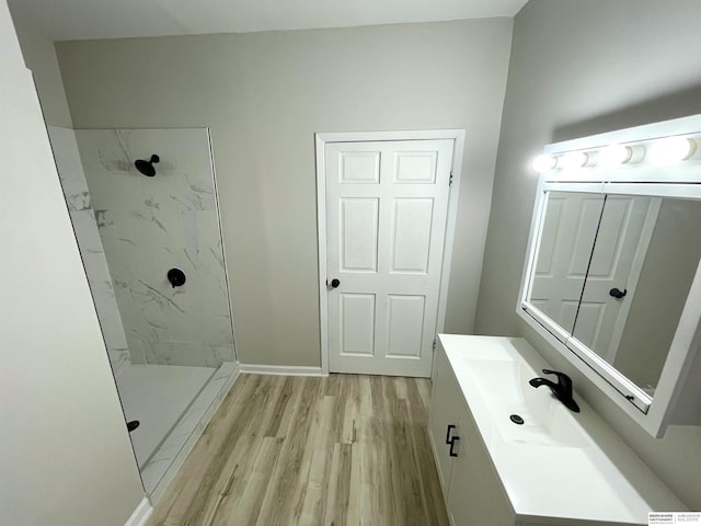 full bathroom featuring vanity, wood finished floors, baseboards, and a marble finish shower