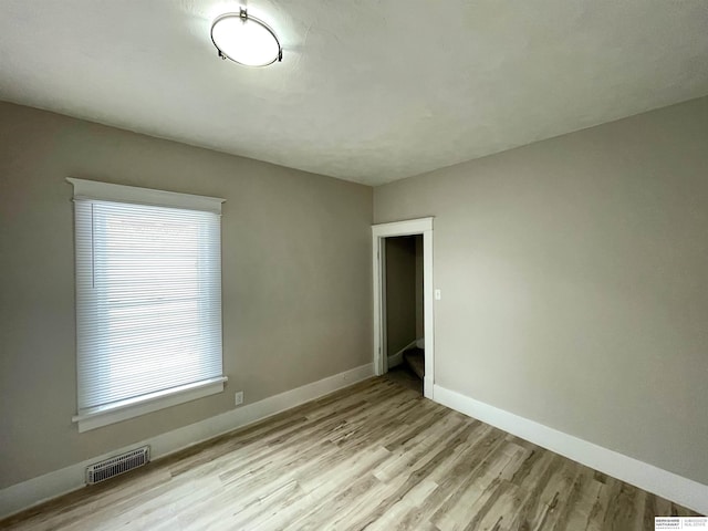 empty room featuring wood finished floors, visible vents, and baseboards