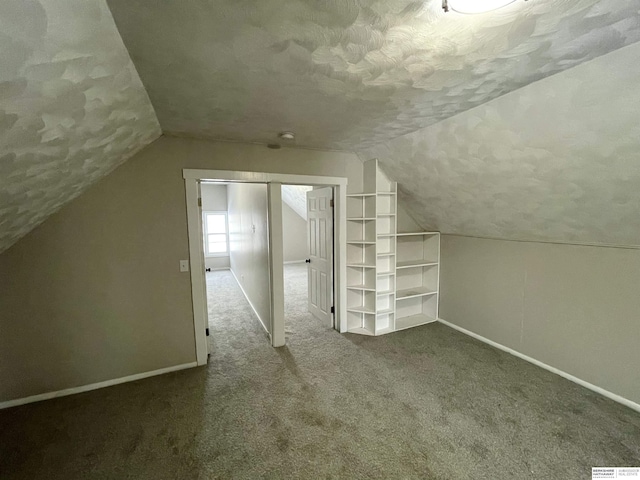 bonus room featuring lofted ceiling, baseboards, carpet floors, and a textured ceiling