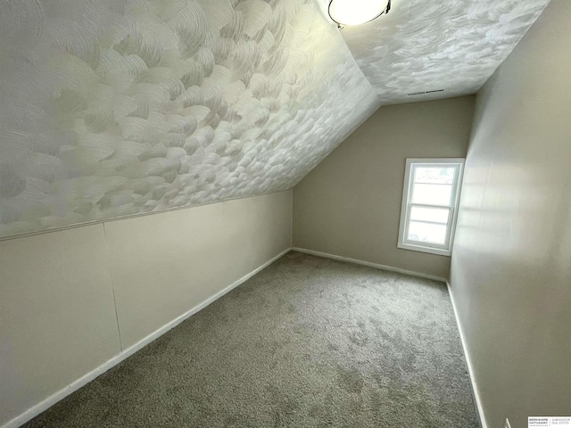 bonus room with baseboards, a textured ceiling, lofted ceiling, and carpet