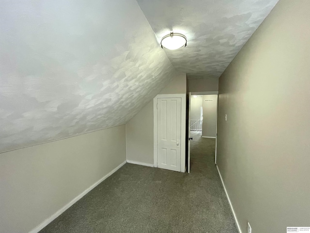 bonus room with vaulted ceiling, baseboards, dark carpet, and a textured ceiling