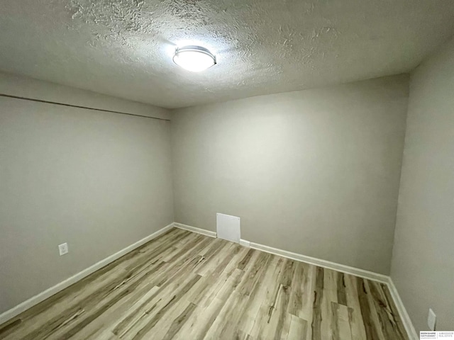 empty room featuring a textured ceiling, baseboards, and wood finished floors