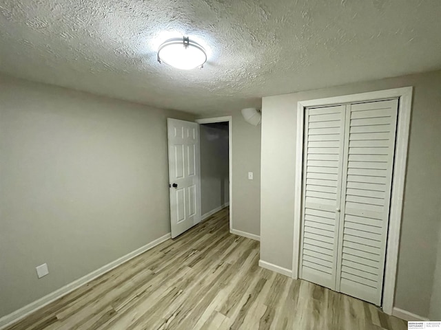 unfurnished bedroom with baseboards, a closet, light wood finished floors, and a textured ceiling