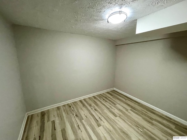 interior space with baseboards, a textured ceiling, and wood finished floors