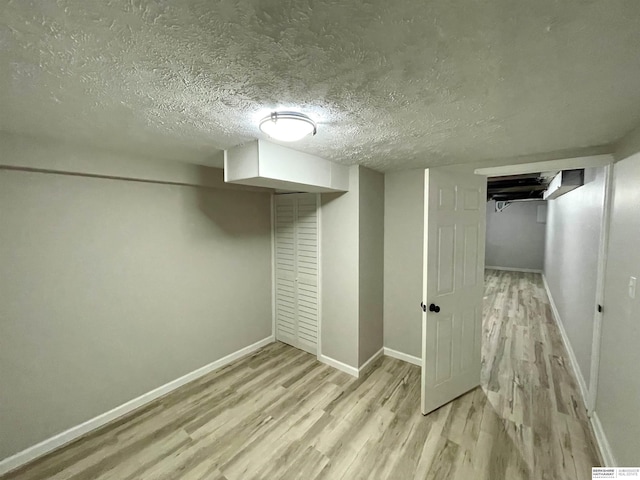 finished basement with wood finished floors, baseboards, and a textured ceiling