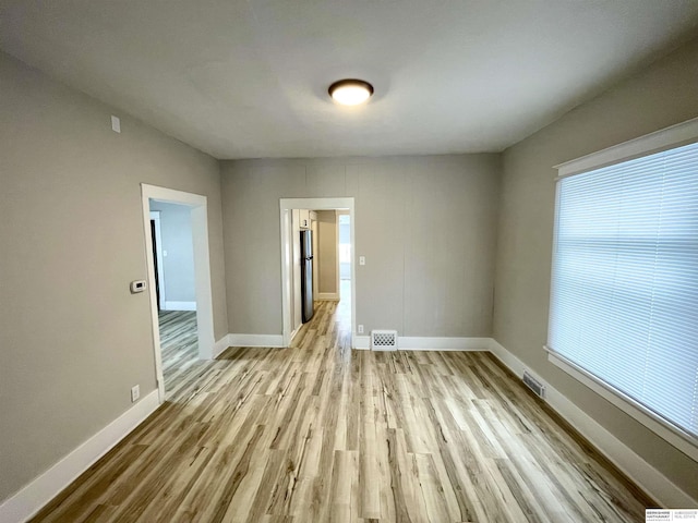 empty room featuring visible vents, baseboards, and wood finished floors