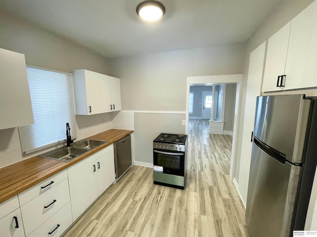 kitchen with a sink, stainless steel appliances, butcher block counters, and light wood finished floors