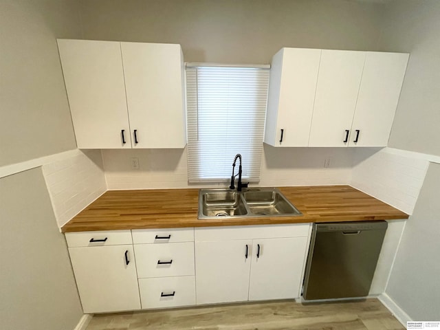 kitchen featuring a sink, wooden counters, stainless steel dishwasher, and white cabinets