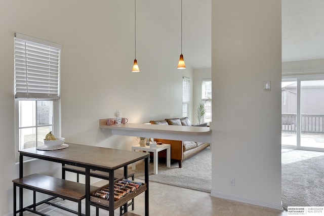 dining space with baseboards, light carpet, and a high ceiling