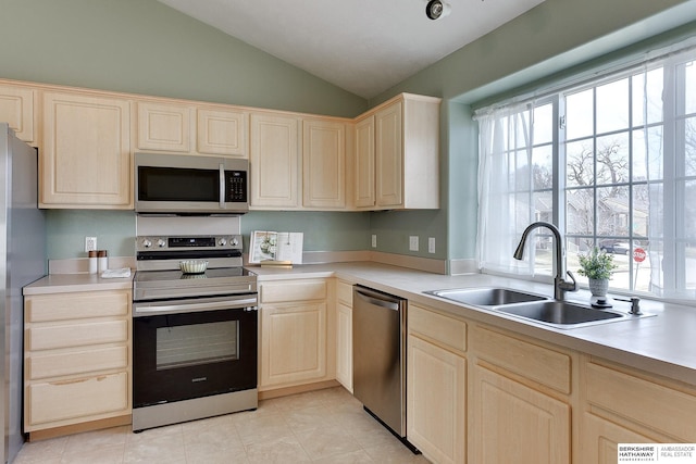 kitchen with light brown cabinetry, a sink, stainless steel appliances, light countertops, and lofted ceiling