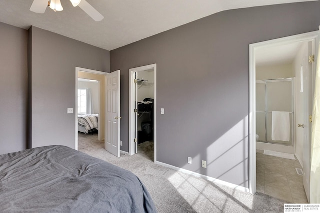 carpeted bedroom featuring tile patterned floors, a walk in closet, a ceiling fan, a closet, and baseboards