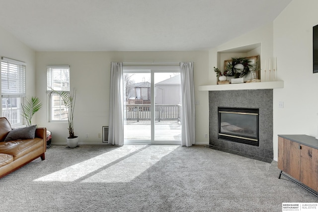 carpeted living room featuring a tile fireplace, baseboards, and lofted ceiling