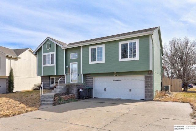 split foyer home with central air condition unit, driveway, and a garage