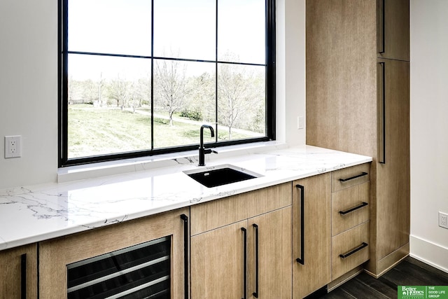 kitchen featuring dark wood-type flooring, wine cooler, light stone countertops, and a sink