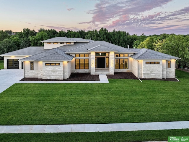 view of front facade featuring a front lawn, concrete driveway, stone siding, and stucco siding