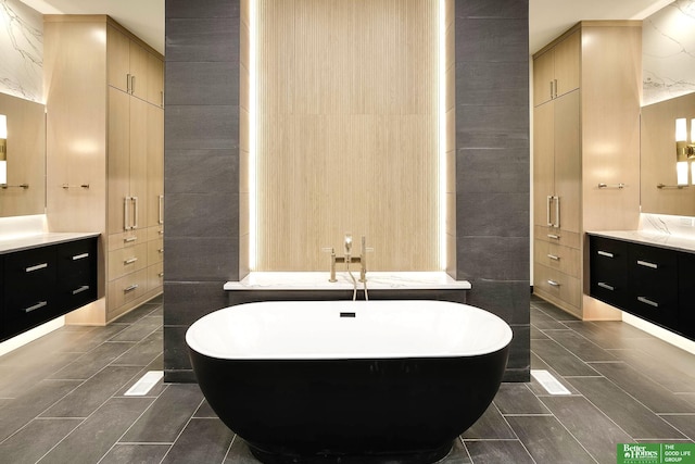 bathroom featuring tile walls, vanity, and a freestanding tub