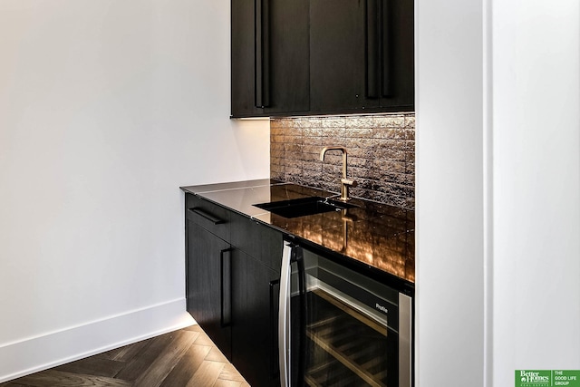 bar featuring beverage cooler, a sink, baseboards, decorative backsplash, and wet bar