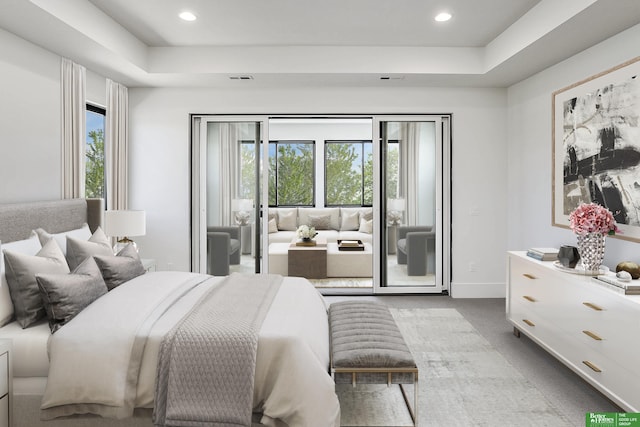 bedroom featuring multiple windows, a raised ceiling, and access to outside